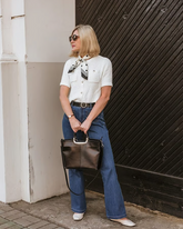 a lady wears a scarf with a white short sleeve cardigan and jeans